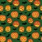 Halloween seamless pattern with orange pumpkins carved faces and black bats on green background