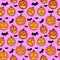 Halloween seamless pattern with orange pumpkins carved faces and black bats on pink background