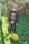 Halloween skeleton child. Child play outdoors. Cheerful child and pumpkin on sunshine background. Happy little boy.
