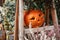 Halloween street decor. Jack o lantern pumpkins and flowers in city street, holiday decor of garden and buildings. Autumn market