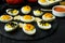 Halloween stuffed eggs with cheese and mustard on a black stone.