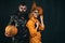 Halloween surprised woman and handsome bearded man in Halloween hat and costume holding pumpkin.