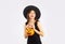 Halloween theme young asian woman in black costume wearing witch hat carrying pumpkin lantern on white background