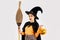 Halloween theme, young asian woman in witch costume holding broom and carrying orange pumpkin bucket lantern posing on white