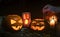 Halloween themed background, spooky pumpkins and a person hand turning on the candles in a dark setting