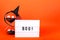 Halloween themed cinema light box on orange background with funny witch hat and black sand hourglass
