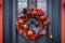 A Halloween themed wreath on a front door with bats, spiders, and pumpkins