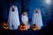 Halloween, three dogs sit disguised as ghost and witch in front