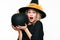 Halloween Witch with shocked expression holding large black pumpkin. Beautiful young woman in witch hat holding pumpkin.