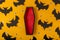 A Halloween yellow background with many plastic eyes, bats and an open black and red coffin in the center. Festive flat lay. A