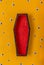 Halloween yellow background with an open red-black coffin in the center, around a scattering of plastic eyes of different sizes. A