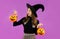 Halloween, young asian girl in black costume wearing black witch hat holding and carrying orange pumpkin bucket on purple