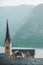 hallstatt church with bell tower lake with alpine mountains on background