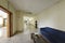 Hallway of an office with a blue velvet three-seater sofa, wood and glass side table and marble floors