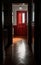 A hallway in a suburban home with a polished dark hardwood floor and a red front door