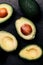 Halved avocados over black background. Top view. Avocado spread.