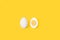 Halved boiled egg and an egg on a yellow background