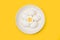 Halved boiled egg and five eggs on a white plate on a yellow background