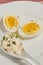 Halved, hard boiled egg and spoon of mayo with shreded basil