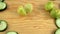 Halved limes and fresh cucumber slices on wooden cutting board