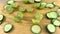 Halved limes and fresh cucumber slices on wooden cutting board