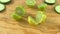 Halved limes and fresh cucumber slices on wooden cutting board