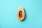 Halved papaya on blue background. Top view. Copy space. Summer time. Tropical travel, exotic fruit. Vegan and vegetarian concept