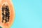 Halved papaya on blue background. Top view. Copy space. Summer time. Tropical travel, exotic fruit. Vegan and vegetarian concept