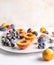 Halved peaches, nectarines, grapes, figs on white plate, cutlery on white tablecloth, front view