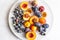Halved peaches, nectarines, grapes, figs on white plate on white tablecloth