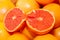 Halved pink grapefruit, on pile of whole grapefruits