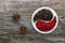 A halved porcelain bowl filled with black and red peppercorns on an aged rough board. Star anise inflorescences lie nearby