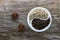 A halved porcelain bowl filled with black and white peppercorns on an aged rough board. Star anise inflorescences lie nearby