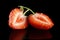 Halved strawberry isolated on black with green stalk