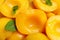 Halves of canned peaches with mint leaves as background, closeup