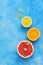 Halves of citrus fruits in a row on a blue background. Orange, lemon, grapefruit and small yellow flowers of Buttercup. The view f