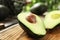 Halves of delicious ripe avocado on board against blurred background