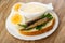 Halves of eggs, sandwich with sprats, bowl with mayonnaise in plate on wooden table