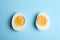 Halves of fresh hard boiled chicken egg on blue background, flat lay