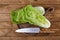 Halves of fresh ripe Chinese cabbage and knife on wooden table, flat lay