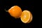 Halves of lemon and drops of juice isolated on black background of juice