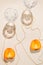 Halves of persimmon fruit and two glasse with water on beige pastel background with pearl necklace. Summer refreshment concept.