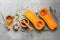 Halves of raw pumpkin or butternut squash with herbs,honey and garlic for cooking on gray rustic background. Top view, flat lay