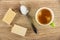 Halves of wafer, spoon with sugar, coffee in cup on table. Top view