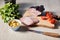 Ham on cutting board with knife, parsley, cherry tomatoes, olives on wooden table