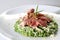 Ham and parmesan risotto with pesto on a white plate
