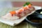Hamachi sushi on white plate along with Japanese sauce and green