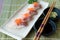 Hamachi sushi on white plate along with Japanese sauce and green