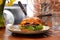 Hamburger with beef, mutton, vegetables, sauce and challah bun, on a plate, side view.