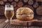 Hamburger with cheddar cheese, a glass of beer and firewood pile in background - Close-up